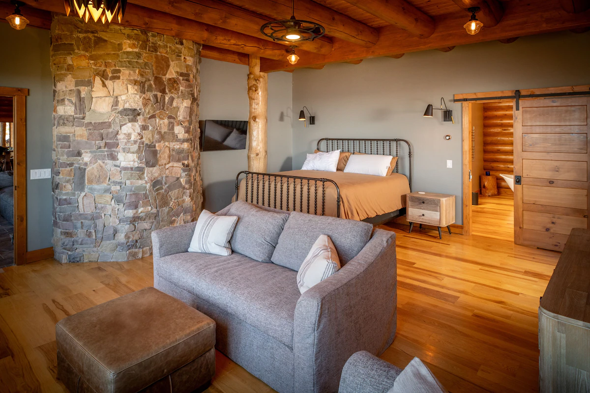 Bedroom with upholstered seating, stone feature and open bathroom doorway
